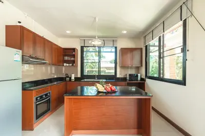 a kitchen with wooden cabinets and a bowl of fruit on a counter at 3 Bedrooms villa walking distance to Rawai beach in Rawai Beach