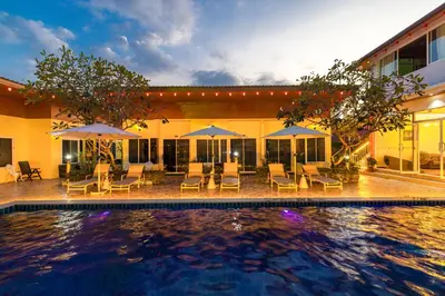 a pool with chairs and umbrellas in front of a building at Tongtong Garden Holiday Hotel\u666e\u5409\u5c9b\u901a\u901a\u82b1\u56ed\u9152\u5e97 in Rawai Beach