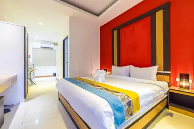 a bedroom with a large bed with a red wall at Tongtong Garden Holiday Hotel\u666e\u5409\u5c9b\u901a\u901a\u82b1\u56ed\u9152\u5e97 in Rawai Beach