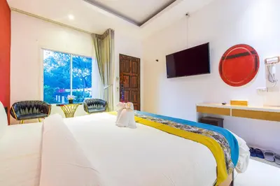 a bedroom with a white bed with a tv on the wall at Tongtong Garden Holiday Hotel\u666e\u5409\u5c9b\u901a\u901a\u82b1\u56ed\u9152\u5e97 in Rawai Beach