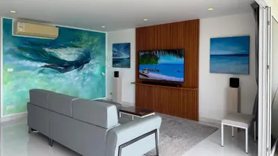 a living room with a couch and a tv at Karon Butterfly Seaview Home in Phuket Town