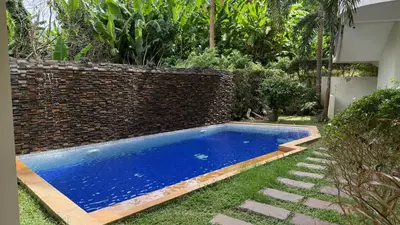 a swimming pool in a yard next to a brick wall at Karon Butterfly Seaview Home in Phuket Town