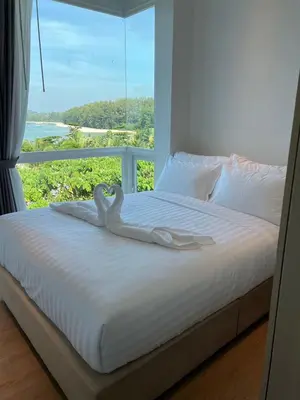 a white bed with a swan towel on it at Beachfront Bliss at Naiyang Phuket by ALPHATEL in Phuket