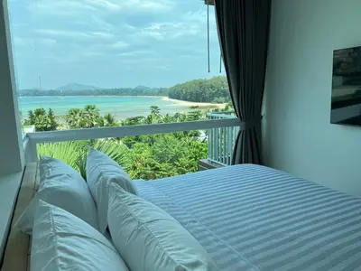 a bed in a room with a view of the ocean at Beachfront Bliss at Naiyang Phuket by ALPHATEL in Phuket