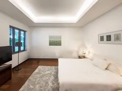 a white bedroom with a bed and a television at Charming 3-bdr apartment with pool in Bang Tao Beach