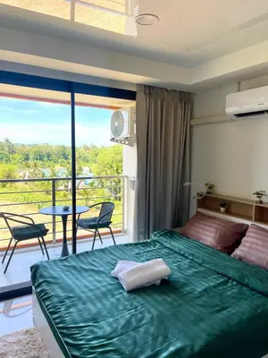 a bedroom with a large green bed and a balcony at Cozy Room Phuket in Ban Mai Salae