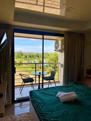 a bedroom with a bed and a balcony with a table and chairs at Cozy Room Phuket in Ban Mai Salae