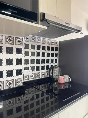 a kitchen with a black and white tiled wall at Cozy Room Phuket in Ban Mai Salae