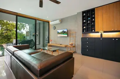 a living room with a leather couch and a table at Private & Modern 4BR Pool Villa Otero, 3 Levels of Comfort with Greenery Views, Kamala in Kamala Beach