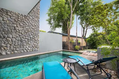 a swimming pool with chairs and a stone wall at Private & Modern 4BR Pool Villa Otero, 3 Levels of Comfort with Greenery Views, Kamala in Kamala Beach