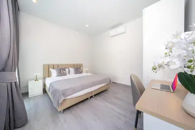 a white bedroom with a bed and a desk at Villa with swimming pool in Ravai 17 in Ban Saiyuan (1)