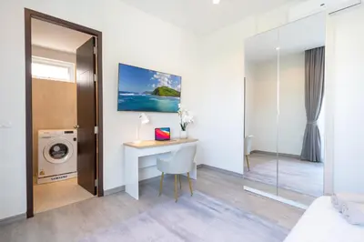 a bedroom with a desk and a washing machine at Villa with swimming pool in Ravai 17 in Ban Saiyuan (1)