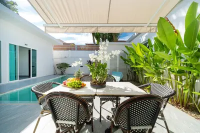 an outdoor dining room with a table and chairs at Villa with swimming pool in Ravai 17 in Ban Saiyuan (1)