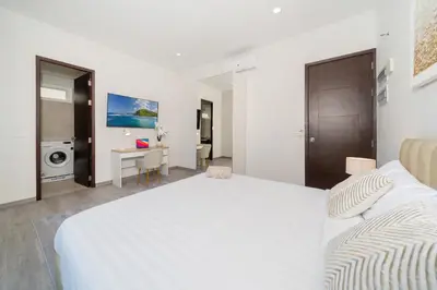 a white bedroom with a bed and a desk at Villa with swimming pool in Ravai 17 in Ban Saiyuan (1)