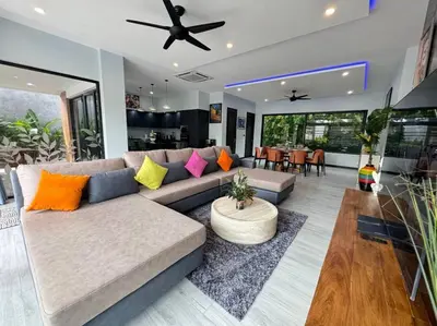 a living room with a couch with colorful pillows at Luciana Villa by G Estate Phuket in Rawai Beach