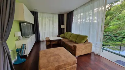 a living room with a couch and a large window at Просторная квартира с одной спальней in Kamala Beach