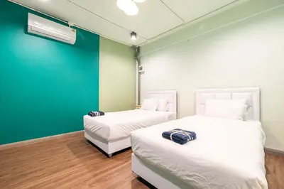 two beds in a room with a green wall at Queen On Street Guest House in Ban Lo Long