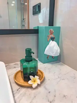 a bathroom counter with a bottle of perfume and a flower at 5 Star La Vita Studio Rawai 702 in Phuket Town