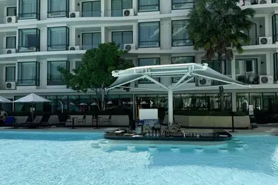 a swimming pool with a white umbrella in front of a building at 5 Star La Vita Studio Rawai 702 in Phuket Town