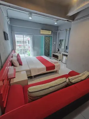 a bedroom with a large bed and a red couch at Madam Inn Patong in Patong Beach