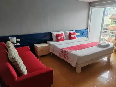 a bedroom with a large bed and a red couch at Madam Inn Patong in Patong Beach