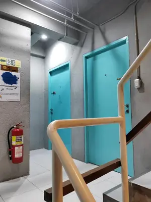 two blue doors in a room with a fire extinguisher at Madam Inn Patong in Patong Beach