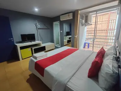 a bedroom with a large bed with a red blanket at Madam Inn Patong in Patong Beach