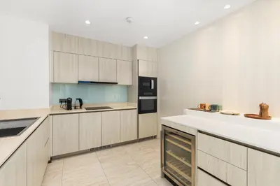 a kitchen with wooden cabinets and white counter tops at Beachfront 3BR Penthouse with Private Rooftop Pool - Laguna, BangTao in Phuket Town