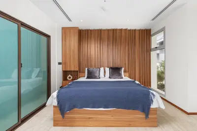 a bedroom with a large bed and a glass wall at Beachfront 3BR Penthouse with Private Rooftop Pool - Laguna, BangTao in Phuket Town
