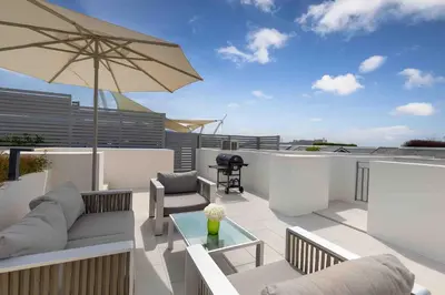 a patio with a couch and an umbrella on a roof at Beachfront 3BR Penthouse with Private Rooftop Pool - Laguna, BangTao in Phuket Town