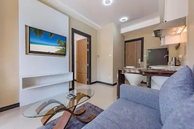 a living room with a blue couch and a desk at Tropical Bliss, Relax & Enjoy at 1BR Apartment MBC near Mai Khao Beach! in Mai Khao Beach