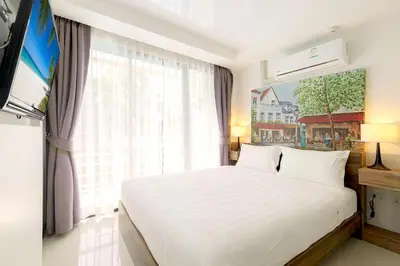 a bedroom with a white bed and a large window at Tropical Bliss, Relax & Enjoy at 1BR Apartment MBC near Mai Khao Beach! in Mai Khao Beach