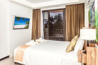 a white bedroom with a bed and a window at Tropical Bliss, Relax & Enjoy at 1BR Apartment MBC near Mai Khao Beach! in Mai Khao Beach
