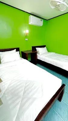two beds in a room with a green wall at Alanta aonang resort in Ban Khlong Haeng