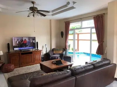 a living room with a leather couch and a tv at Luxury Pool Villa by Golf Courses & Elephant Sanctuary in Kathu