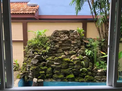 a stone wall in front of a building with a fish tank at Luxury Pool Villa by Golf Courses & Elephant Sanctuary in Kathu