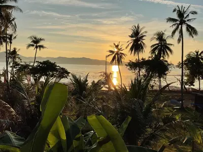 a view of a beach with palm trees and the ocean at Baan Suan Sunset in Ban Laem Sai