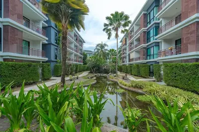 a pond in the courtyard of a building with palm trees at C201 Neatest Apartment The title 50m to beach and shops in Rawai Beach