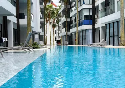 a large swimming pool with chairs in front of a building at Cozy 1BR Apartment with Big Balcony - 2 Pools & 5 mins from Surin Beach in Phuket Town