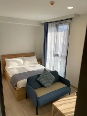 a bedroom with a bed with a blue chair and a window at Studio Apartment, Bang Tao Phuket in Laguna Phuket
