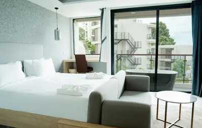 a bedroom with a white bed and a couch at Karen Sunset Hotel in Phuket Town