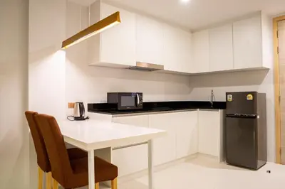 a small kitchen with a table and a refrigerator at Karen Sunset Hotel in Phuket Town
