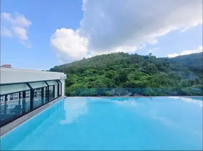 a swimming pool with a mountain in the background at Karen Sunset Hotel in Phuket Town