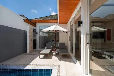 a patio with a table and an umbrella and a pool at The Sense Villa Phuket in Rawai Beach