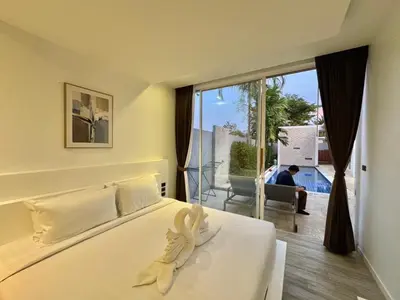a bedroom with a white bed with a large window at The Sense Villa Phuket in Rawai Beach