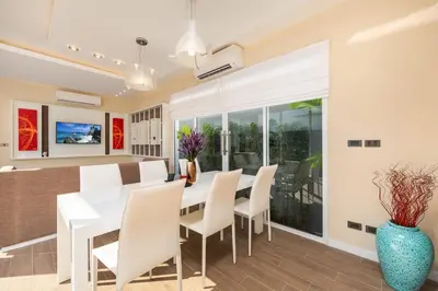 a dining room with a white table and chairs at The Sense Villa Phuket in Rawai Beach