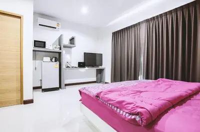a bedroom with a pink bed and a refrigerator at Ra Residence Phuket in Chalong
