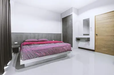 a bedroom with a bed with pink pillows on it at Ra Residence Phuket in Chalong