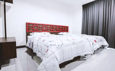 a white bedroom with a bed with a red headboard at Ra Residence Phuket in Chalong