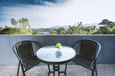 a glass table and two chairs on a balcony at Ra Residence Phuket in Chalong